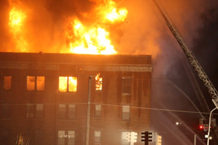 A fire in an apartment building on Walnut St. between 48th and Hanson streets burned into the evening. (Charles Fox / Staff Photographer)