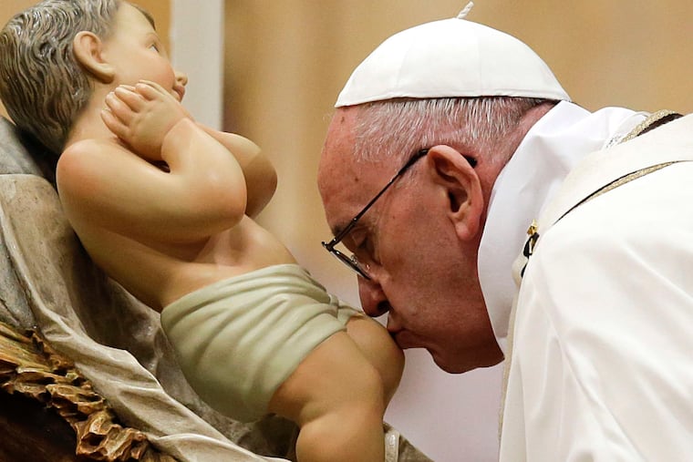 Pope Francis kisses a statue of Baby Jesus as he celebrates Christmas Eve Mass at the Vatican. The pontiff lamented a "culture of indifference, which not infrequently turns ruthless."