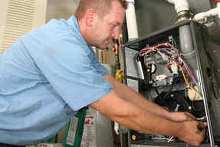 Bovio employee Sean Fitch works on a high-efficiency furnace the company installed in a home in Deptford. (Charles Fox / Staff Photographer)