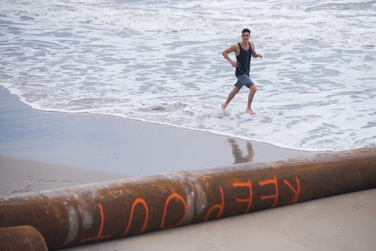 A runnier makes his way toward dredging pipes with “Keep Out” painted on them in Margate.