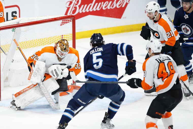 Philadelphia Flyers goaltender Felix Sandstrom (32) makes a save againstWinnipeg Jets' Brenden Dillon (5) during the first period of an NHL hockey game Wednesday, April 27, 2022, in Winnipeg, Manitoba. (John Woods/The Canadian Press via AP)