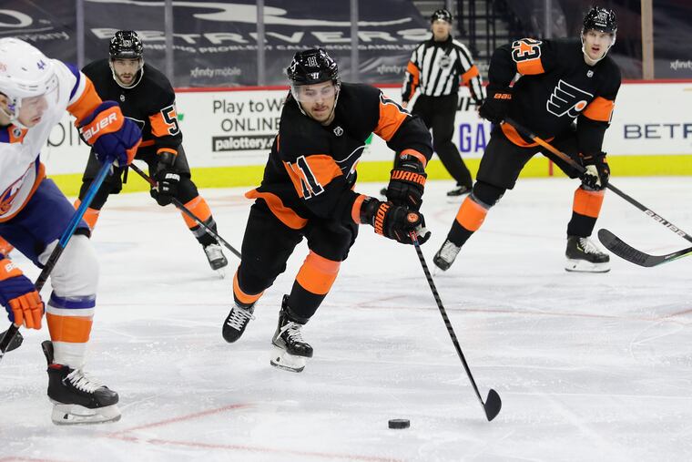 Flyers right winger Travis Konecny reaches for the puck against New York Islanders center Jean-Gabriel Pageau during a game last month. Konecny was placed on the COVID-19 protocol list Sunday.
