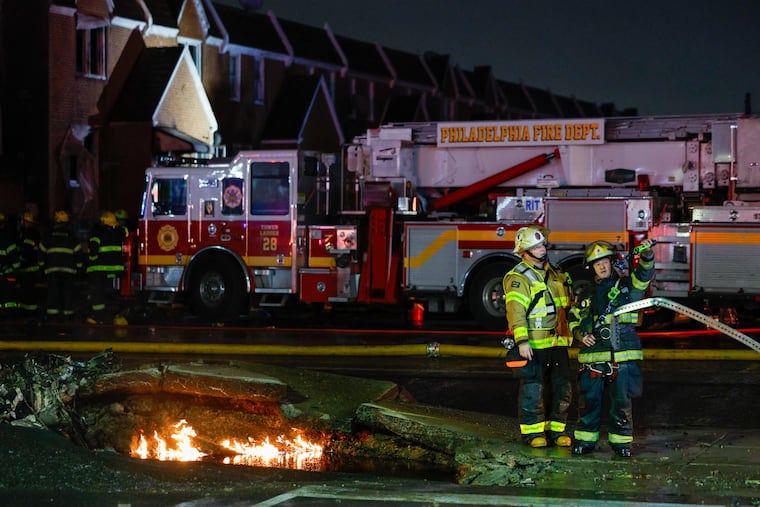 Firefighters work the scene as fire still burns in the impact crater on Cottman Ave., after a plane crashed Friday, Jan. 31, 2025, in Philadelphia