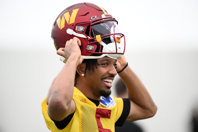 Washington Commanders quarterback Jayden Daniels puts on his helmet during a workout on Wednesday.