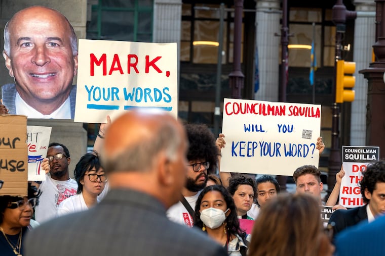 Demonstrators display signs for City Councilmember Mark Squilla (back to camera) outside City Hall in 2023.