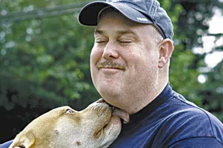 Patrick O'Donnell of Levittown gets a smooch from his dog Otis. O'Donnell is a postal worker who was injured in the anthrax attacks in 2001. (Akira Suwa / Inquirer)