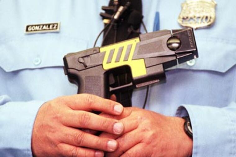 Philadelphia police officer Heladio Gonzalez holds a Taser M26 gun in this file photo. (Ron Tarver / Staff Photographer)