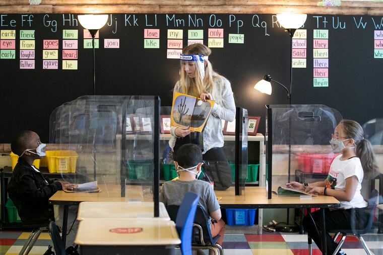 Teacher Lisanne Brown has story time with students, Major Williamson (left), Yahya Elyamani (center) and Jazzmyn Malave at William Dick Elementary School in North Philadelphia on April 27, 2021.