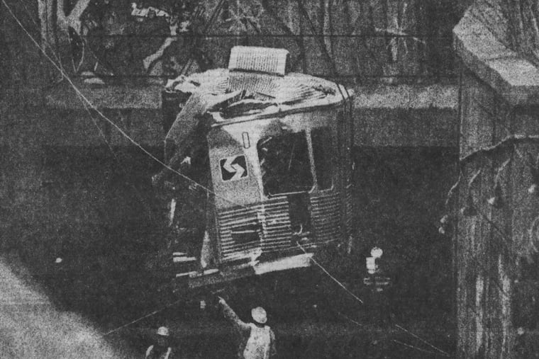 A crowd of spectators gathers as a crane lifts the wrecked train from the subway tunnel's opening.
