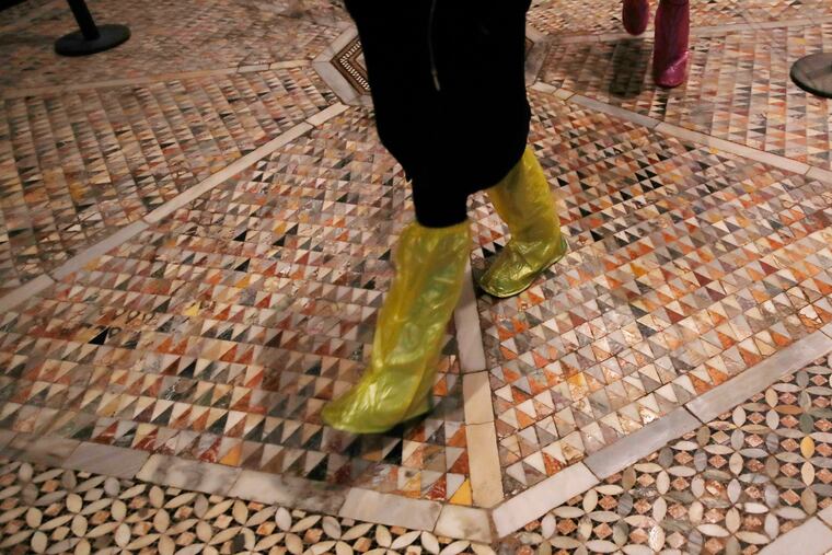People walk on an interior mosaic floor of the St. Mark's Basilica in Venice, Italy, Tuesday, Dec. 17, 2019. Still invisible to the naked eye and the casual visitors, recent flood damage to St. Mark's Cathedral in Venice has been put at 5 million euros (dollars U.S. 5.5 million), the damage is caused by salt which expands as it dries.