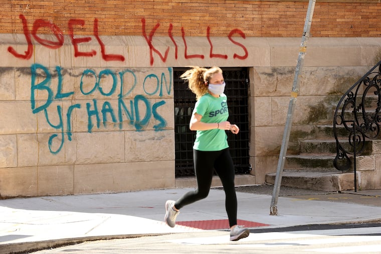A jogger passes the vandalized home belonging to Joel Freedman.