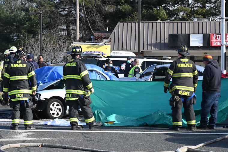 Emergency personnel respond to a motor vehicle collision in Magnolia, N.J. on Wednesday morning. Two people died at the scene and two firefighters were transported to the hospital after a Lawnside Fire Department truck and a car (covered with a tarp) collided at Warwick Road. and White Horse Pike.