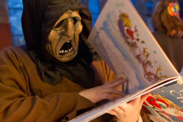 Joey Schaller, 12, of Philadelphia, looks through "The Night Before Christmas,' the book he selected as a Halloween treat from Jen Saemann, October 31, 2011. ( David M Warren / Staff Photographer )