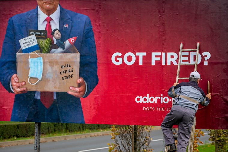 A worker puts up an advertising billboard for a recruiting company, featuring what resembles US President Donald Trump, in Zagreb, Croatia, Saturday, Nov. 7, 2020.