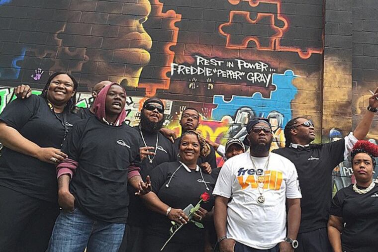 Rapper Freeway, Heal A Woman Heal A Nation volunteers and members of Freddie Gray's community at the site of Gray's new memorial mural (1649 N. Fulton Street, Baltimore). (Instagram / @phillyfreeway)