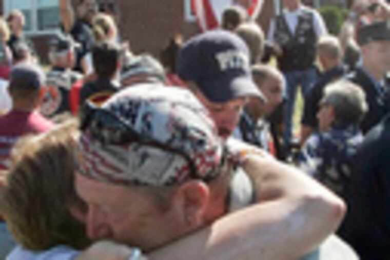 At the Shanksville Volunteer Fire Company, Fire Department of New York workers Christine Lee (left) and Rick Snyder hug near a cross made of steel from the Word Trade Center.