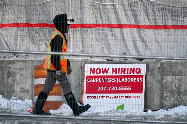 A worker passes a hiring sign at a construction site Wednesday in Portland, Maine.