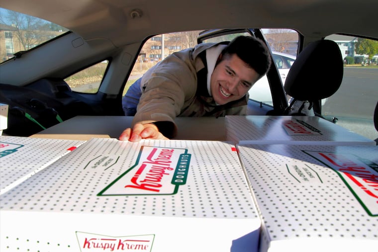 Jayson Gonzalez reaches into his car for another box of Krispy Kreme doughnuts for customers in Little Canada, Minn, who ordered online. Gonzalez, a Minnesota college student, says Krispy Kreme has told him to stop making doughnut runs to Iowa. Gonzalez told the Pioneer Press he was told his sales created a liability for the North Carolina-based company.