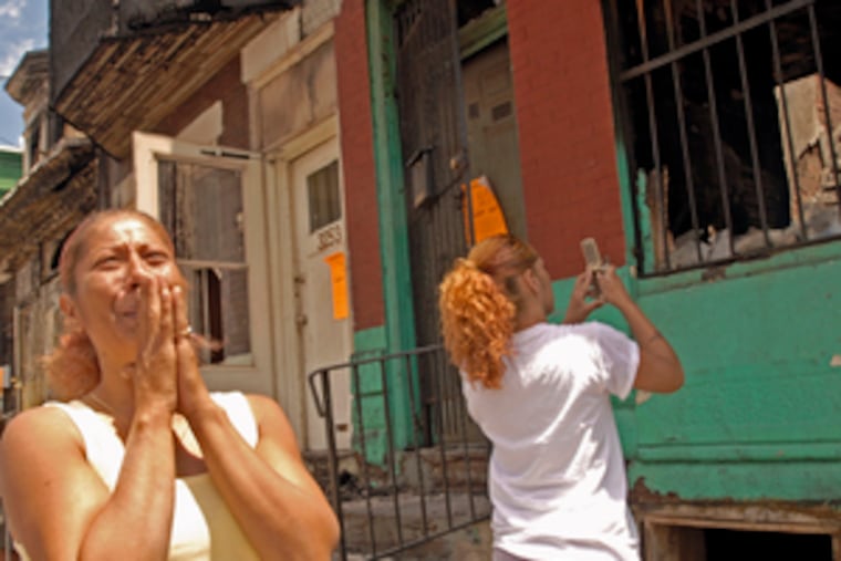 Nancy Malave and daughter Kimberly return to see the remains of their home in Kensington. It was gutted by flames during a fire Wednesday.