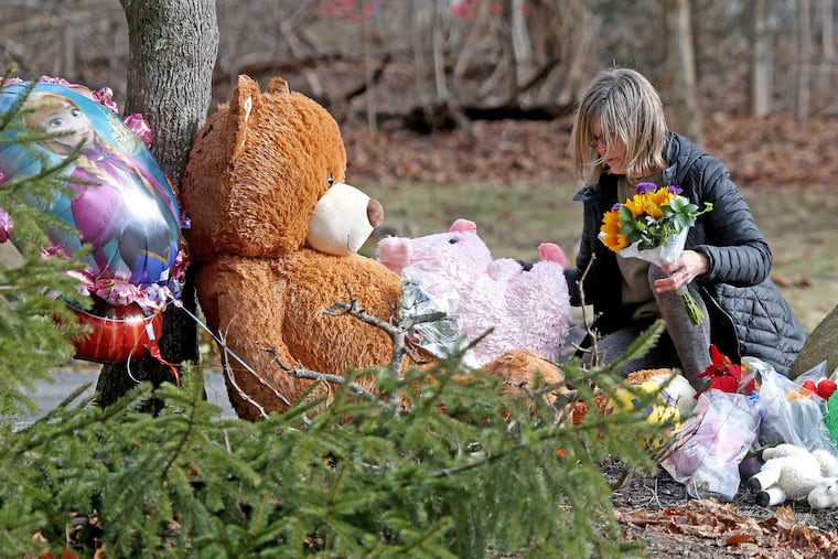 A woman lays flowers down at a makeshift memorial in front of 47 Summer St. on Jan. 26, 2023, in Duxbury, Massachusetts. Lindsay Clancy, 32, has been charged with killing her three children.