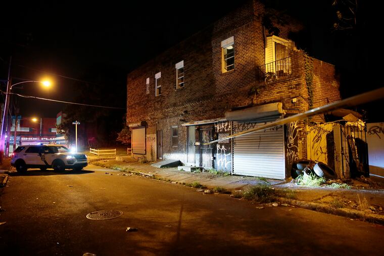 A police officer guards 2622 Warnock St. while detectives seek a warrant to search the building for a gun a man allegedly used to fire at a pair of plainclothes officers as they witnessed a drug deal.