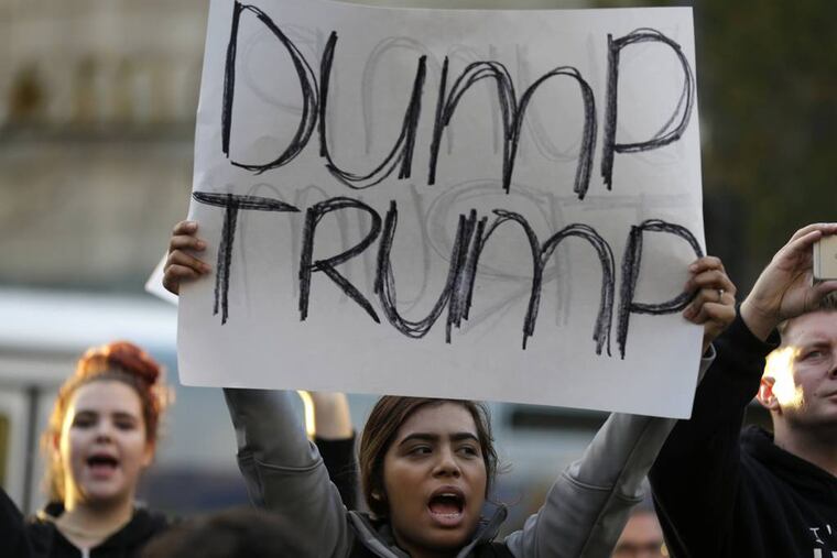 A protester holds a sign that reads "Dump Trump" as she takes part in a protest against the election of President-elect Donald Trump, Wednesday, Nov. 9, 2016, in downtown Seattle.