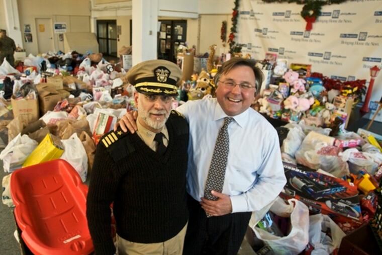 With a backdrop of thousands of toys, Capt. Howard Stephen Serlick, of the Naval Reserve, and Brian Tierney, chief executive of Philadelphia Media Holdings, pose in PMH's lobby yesterday.