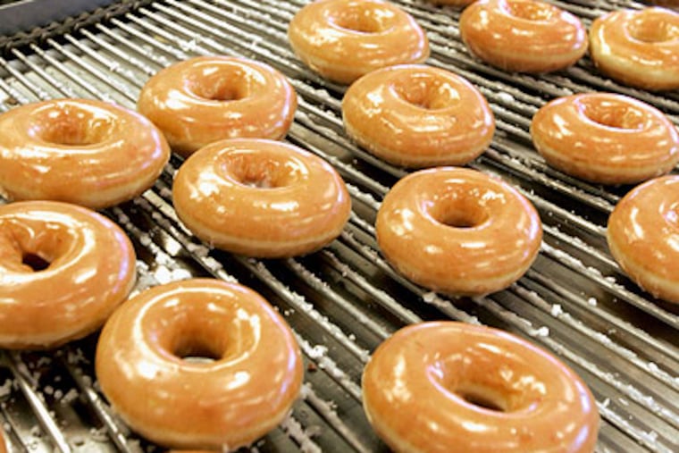 Freshly iced doughnuts roll by on a conveyor belt at a Krispy Kreme store. (AP Photo / Kim Walker)