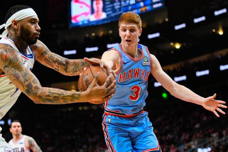 Hawks guard Kevin Huerter and 76ers forward Mike Scott (left) vie for a rebound during the first half.