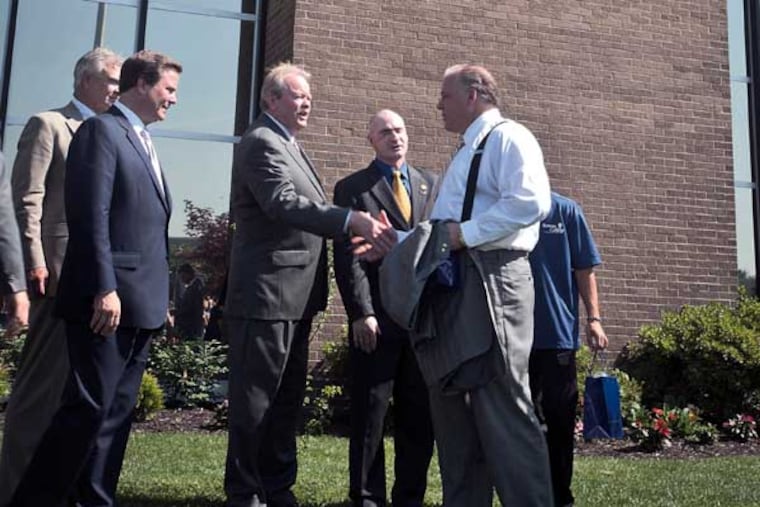Robert M. Damminger, Gloucester County Freeholder Director, (left) shakes hands with New Jersey Senate President Stephen Sweeney as other officials stand by after the unveiling of the new Rowan College At Gloucester County logo on the Eugene J. McCaffrey College Center of the college. ( RON TARVER / Staff Photographer ) July 01 2014