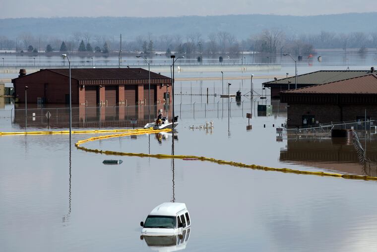 In this March 18, 2019 photo released by the U.S. Air Force, environmental restoration employees deploy a containment boom from a boat on Offutt Air Force Base in Neb., as a precautionary measure for possible fuel leaks in the flooded area. Surging unexpectedly strong and up to 7 feet high, the Missouri River floodwaters that poured on to much the Nebraska air base that houses the U.S. Strategic Command overwhelmed the frantic sandbagging by troops and their scramble to save sensitive equipment, munitions and aircraft.