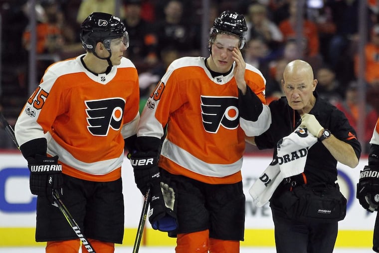 Philadelphia Flyers' Nolan Patrick, center, is helped of the ice by Jori Lehtera, left and a member of the training staff after suffering an injury during the third period of an NHL hockey game against the Anaheim Ducks', Tuesday, Oct. 24, 2017, in Philadelphia. Patrick returned to skate later in the game. The Ducks won 6-2. (AP Photo/Tom Mihalek) .