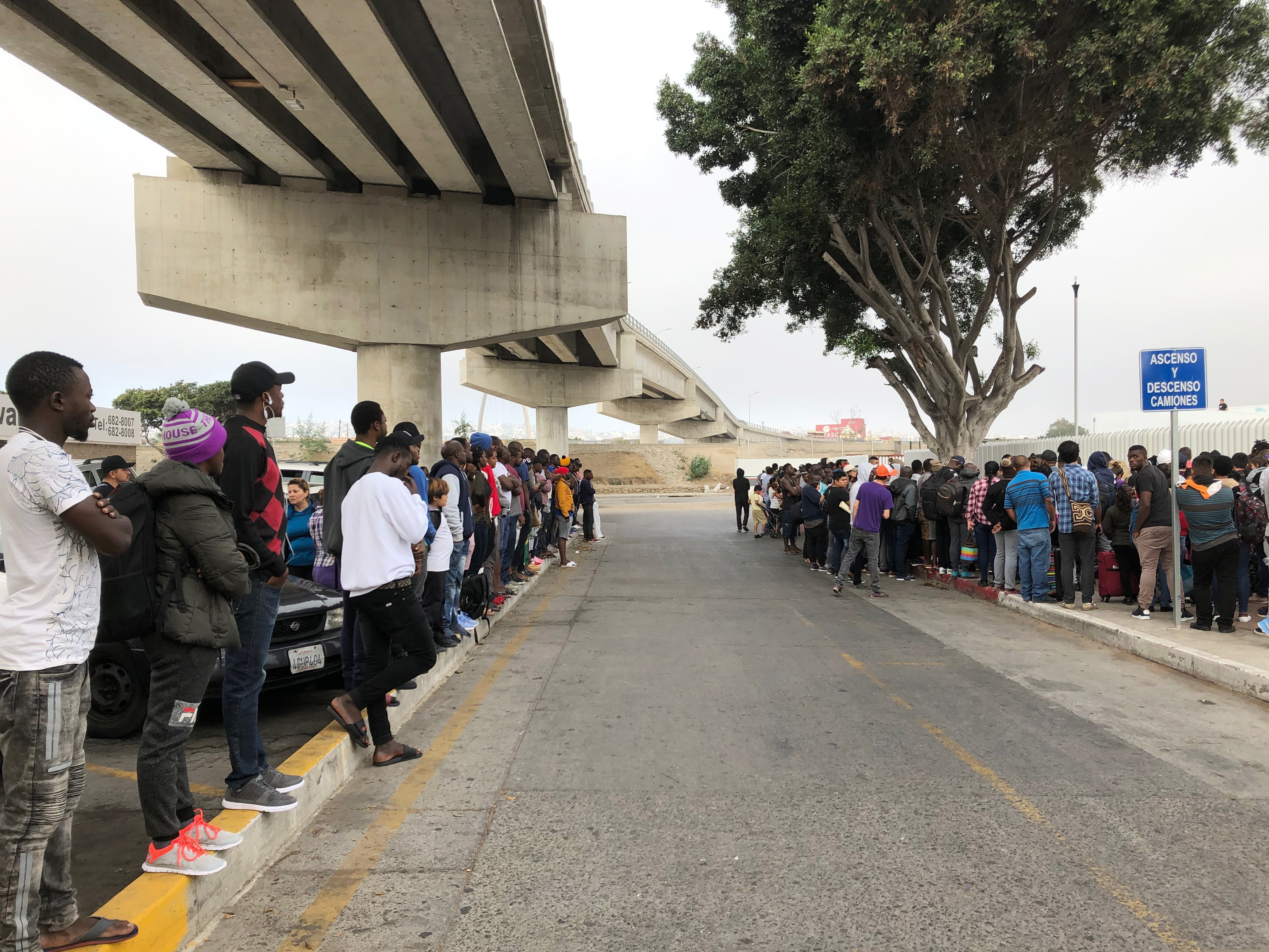 In July, a group of migrants in Tijuana, Mexico, listen to numbers being called for people to claim asylum in the U.S. The long waits are testing the patience of immigrants and border towns.