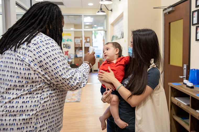 Manda Jaramillo holds her 10-month-old son Lucas Jamarillo while Stephanie Strother takes his temperature at Penn Quarter KinderCare in Washington, D.C. on June 26. MUST CREDIT: Photo by for The Washington Post