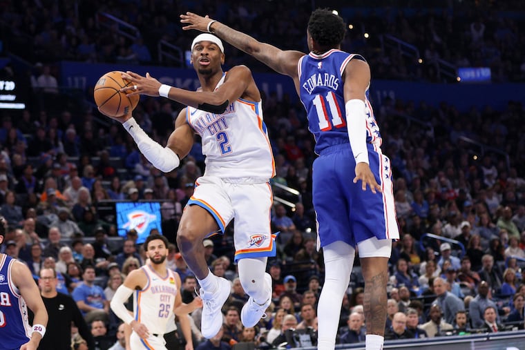 Oklahoma City Thunder guard Shai Gilgeous-Alexander (center) is defended by Sixers forward Justin Edwards during Sunday's game.