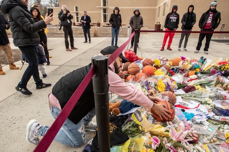 Stephan Sanchez, from Upper Darby, places a basketball where he had written a thank you letter to Kobe Bryant into a memorial in front of Bryant Gymnasium at Lower Merion High School.