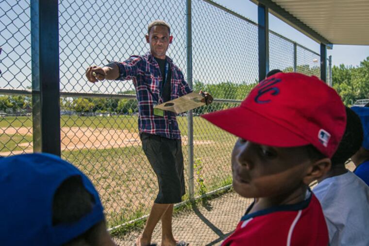 Bryan Morton, founder of North Camden Little League, assigns players positions before a game at Pyne Poynt Park in Camden (MICHAEL BUCHER/For The Inquirer)
