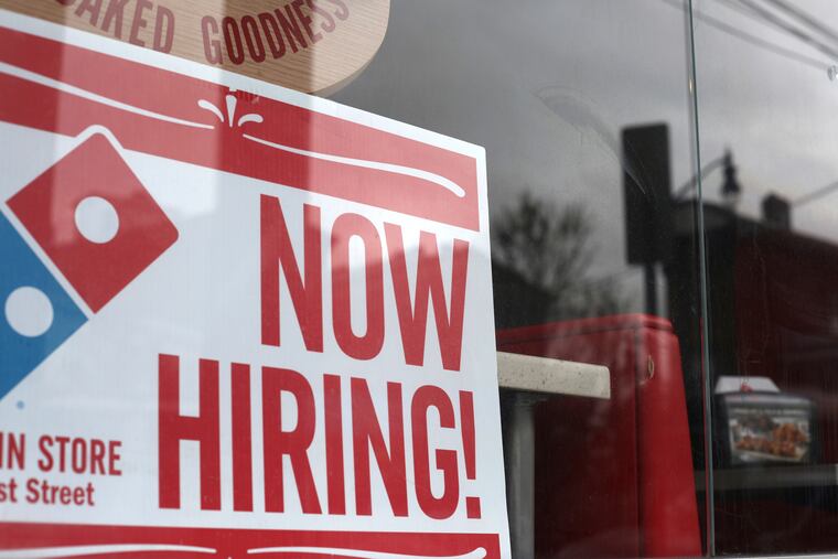 File photo shows a 'now hiring' sign posted at a Domino's Pizza in Jersey City, N.J. Companies that serve consumers face-to-face or deliver food and essentials to homes are eager to hire, including well known names such as Walmart, Amazon, Domino’s, Papa John's, and CVS.