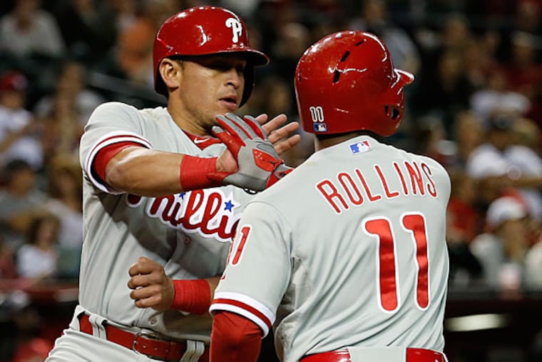 Carlos Ruiz, left, greets Jimmy Rollins after Ruiz scored on a base hit by Ben Revere against the Arizona Diamondbacks during the eighth inning of a baseball game Saturday, April 26, 2014, in Phoenix. (Matt York/AP)