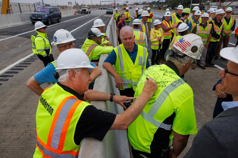 Jim Anderson of Anderson Construction signs the shirt of Rob Buckley with Buckley & Company Inc, shortly before I-95 reopened to vehicles on Friday.