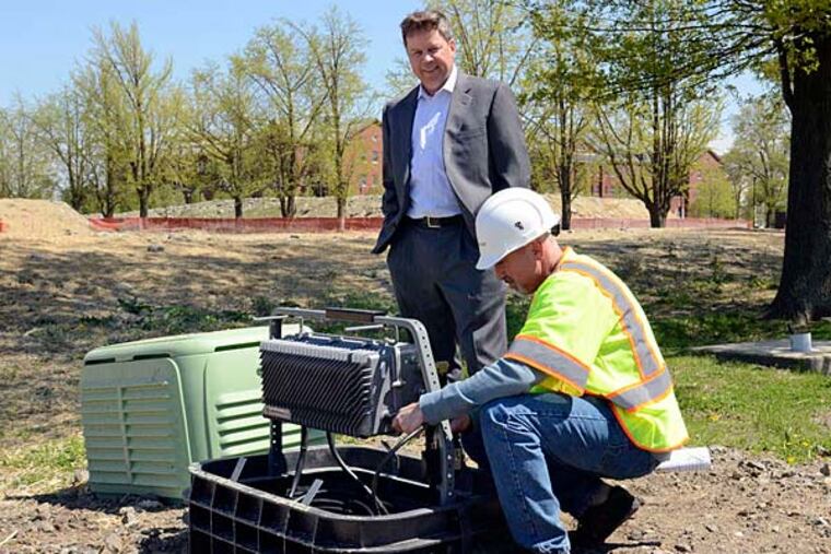 Comcast's Mike Louden (rear) and Jack Clayton at an optical cable junction box at the Navy Yard. TOM GRALISH / Staff Photographer