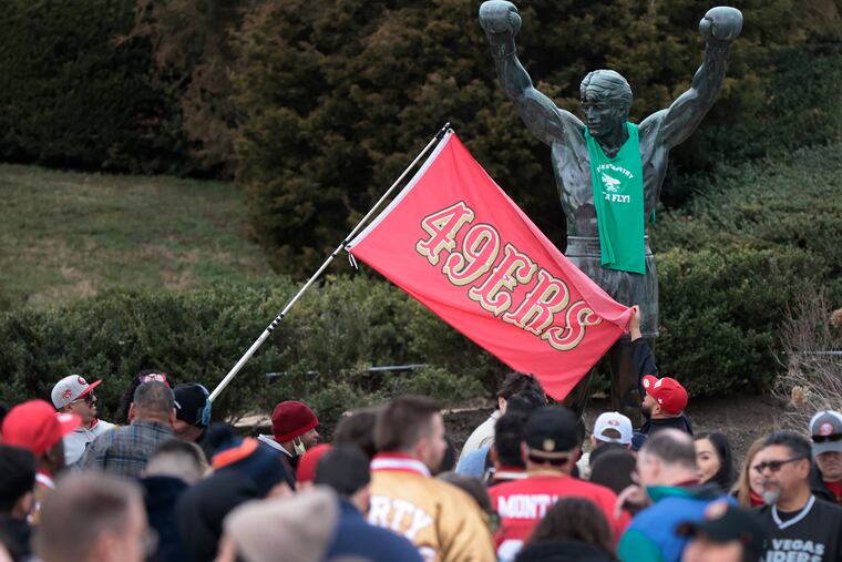 San Francisco fans unfurl their 49ers flag as they visit the Rocky statue at the Art Museum.