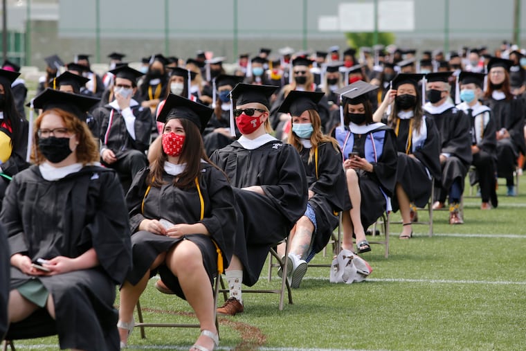 Masked Temple University graduates take their seats during the College of Liberal Arts commencement in 2021. Pandemic-induced work changes and a smaller generation coming into college age raises questions for Philadelphia as stakeholders aim to continue a trend of more college-educated young adults staying in the area.