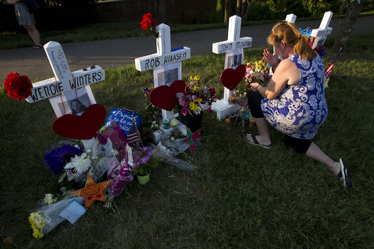 Colleen Joseph prays over the crosses at a makeshift memorial at the scene outside the office building housing The Capital Gazette newspaper in Annapolis, Md., on Sunday, July 1, 2018. Jarrod Ramos is charged with murder after police say he opened fire Thursday at the newspaper.