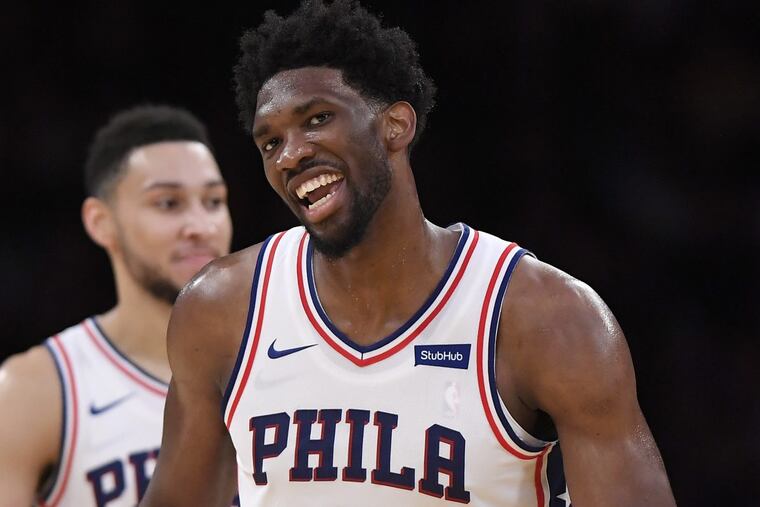 Sixers center Joel Embiid (right) smiles after scoring as guard Ben Simmons stands in the background during the second half of an NBA basketball game against the Lakers on Wednesday.