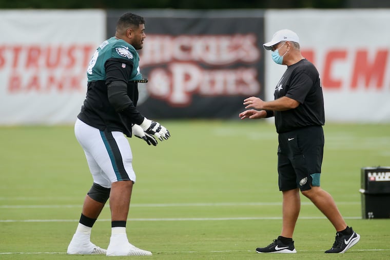 Eagles tackle Jordan Mailata (left) works with offensive line coach Jeff Stoutland during practice last month.