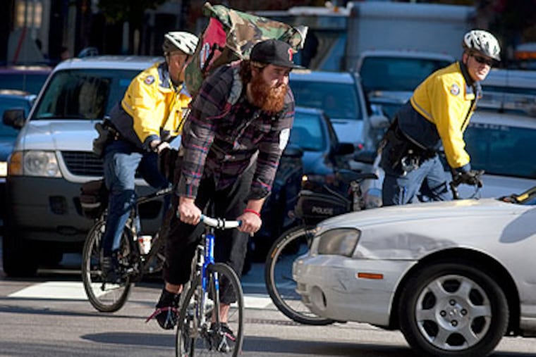 Bike courier John Nunn manuevers his way through traffic as two Philadelphia bicycle policemen pedal nearby. The city is cracking down on cyclists that ride in an unsafe manner. (Ed Hille / Staff Photographer)