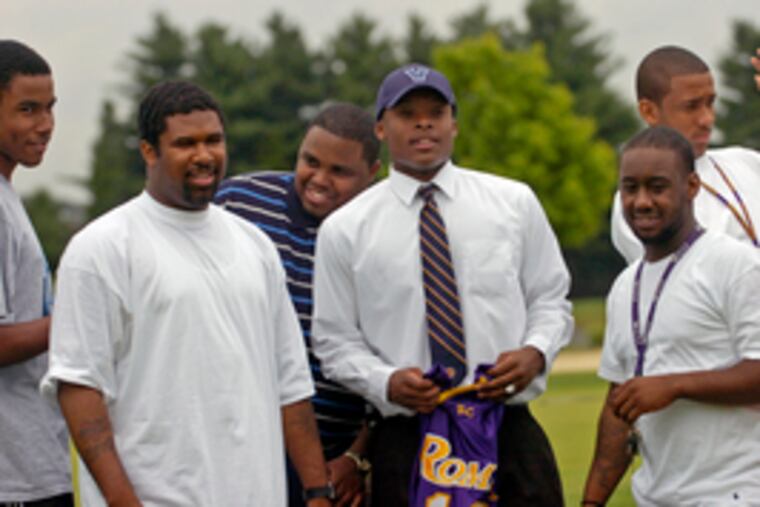 Maalik Wayns (wearing hat) holds his Roman Catholic jersey as teammates congratulate him.