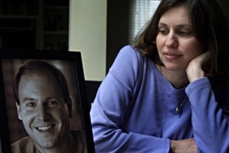 Susan Retik, a co-founder of the widows' support group Beyond the 11th, at home in Needham, Mass., with a portrait of her late husband, David. She will speak in Ambler tomorrow to raise funds for Afghan widows.