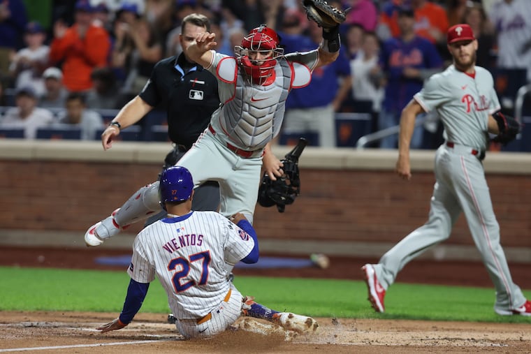 Mets' Mark Vientos slides into home as J.T. Realmuto jumps over him during a Sept. 22 matchup. The Phillies and Mets will meet in the NLDS on Saturday.